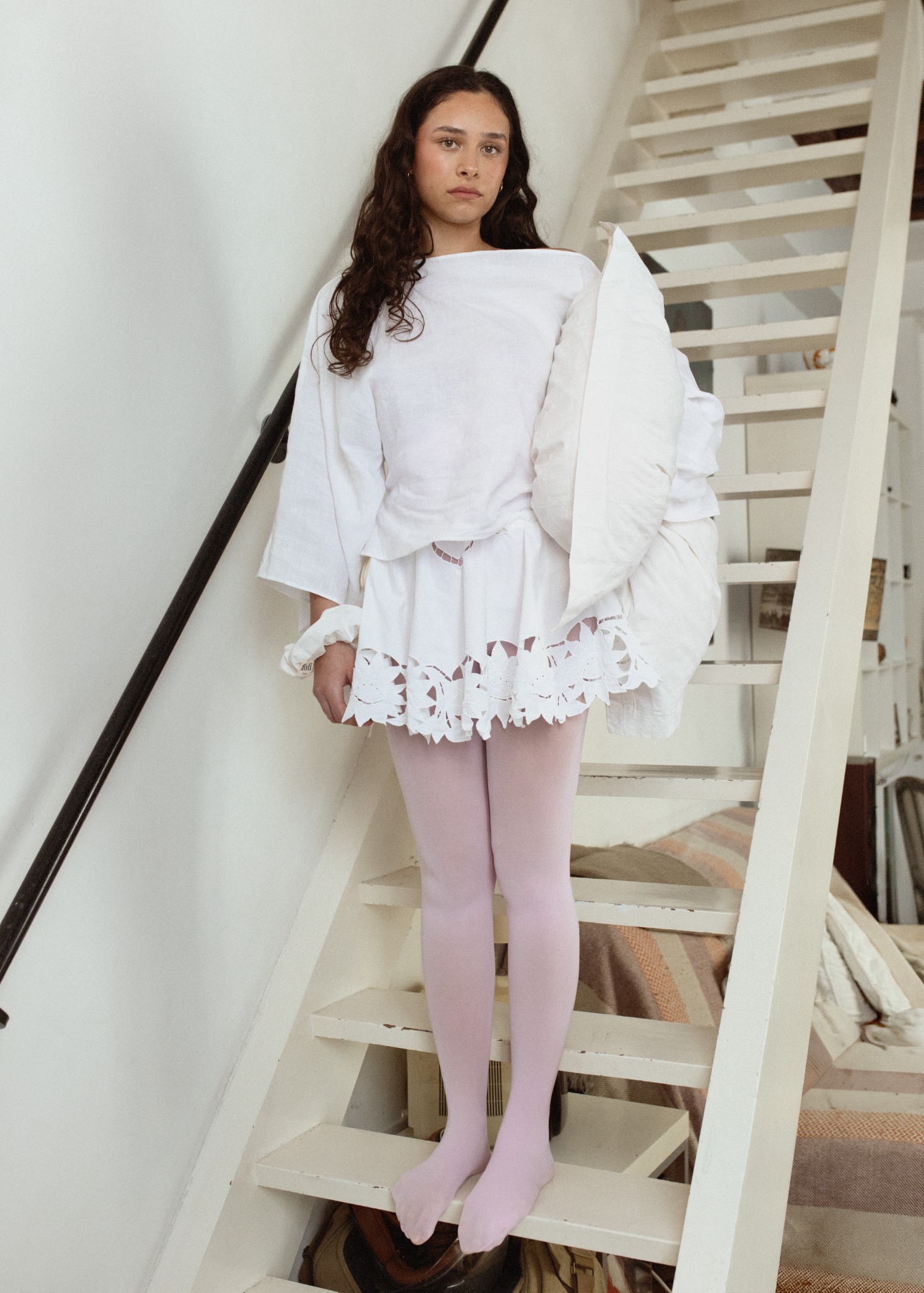 Campagne Foli Paris SS26, silhouette blanche et collants rose pâle dans un escalier