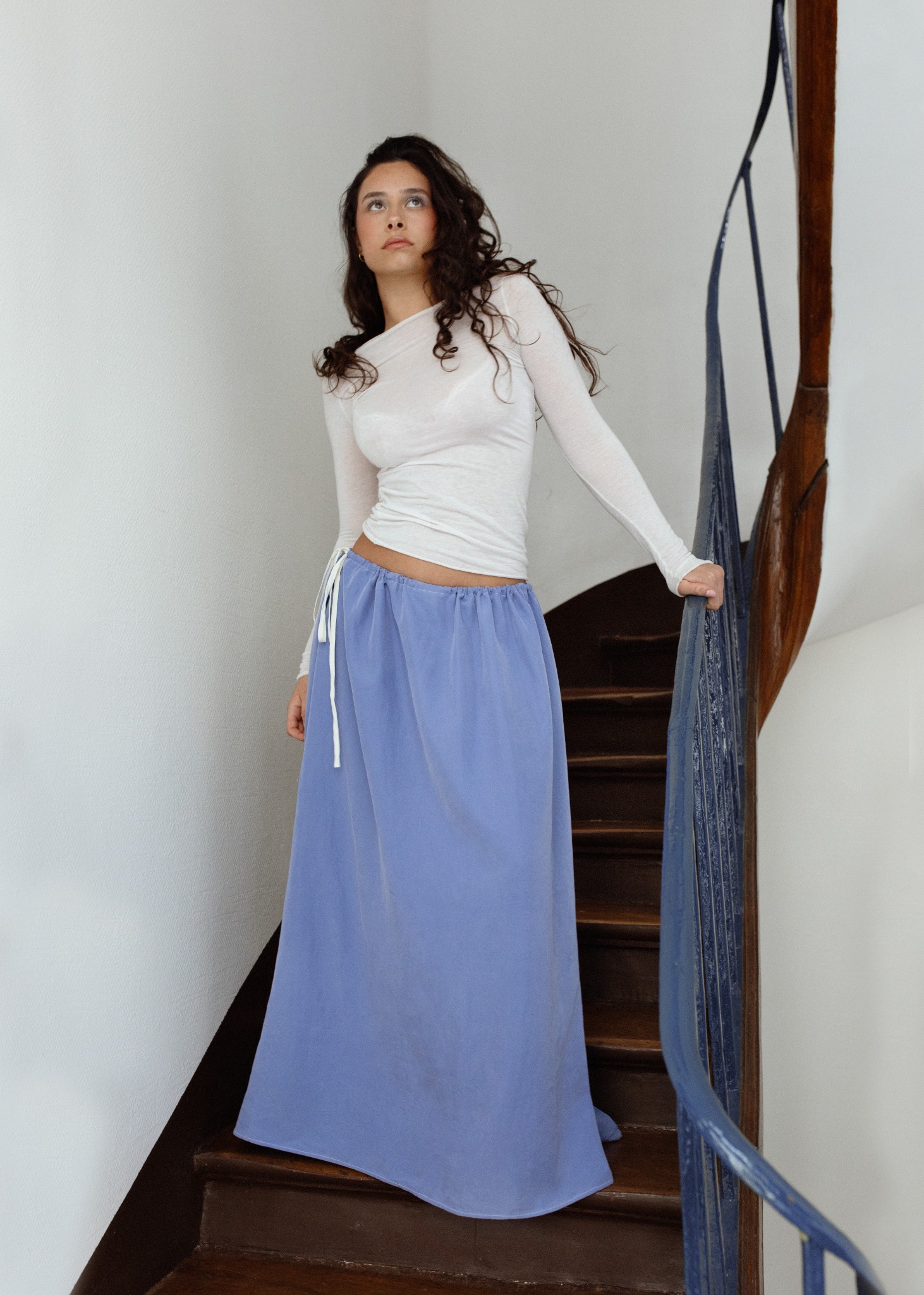 Campagne Foli Paris SS26, jupe bleue dans un escalier